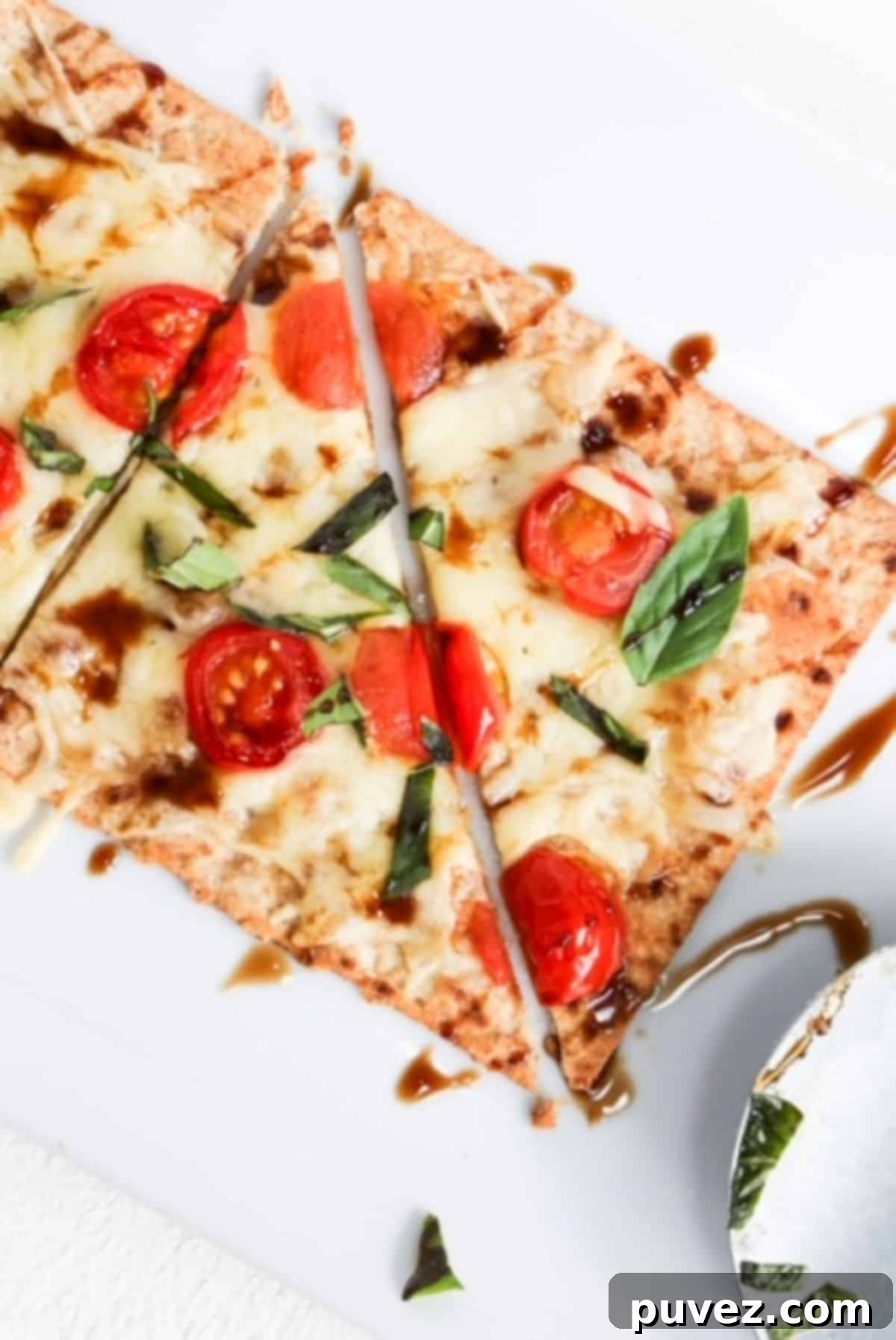 Margherita flatbread on a white plate with a pizza roller to the right.