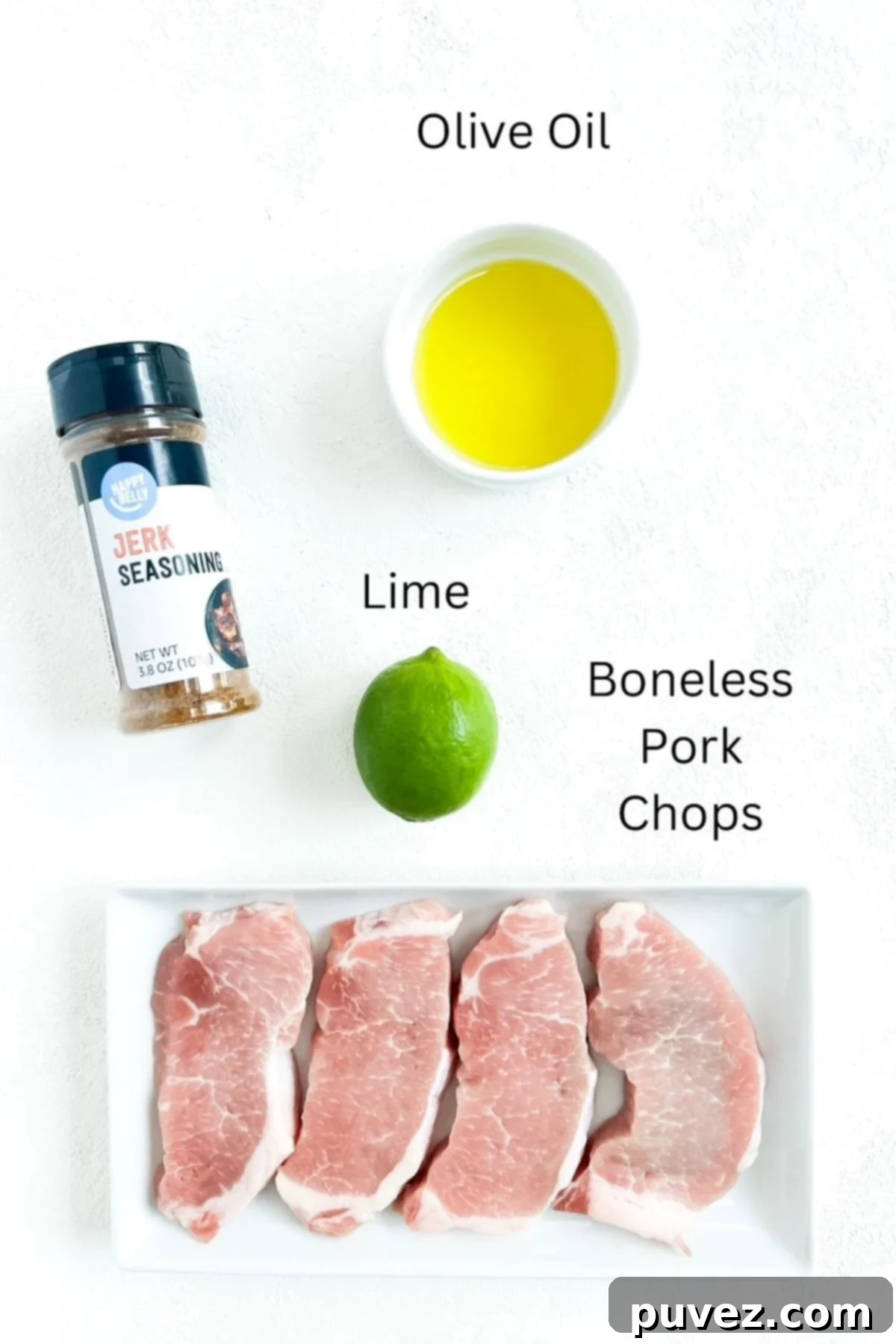 Four boneless pork chops, olive oil, one lime, labeled and a container of jerk seasoning on a white background.