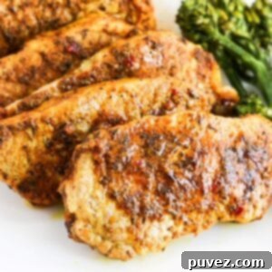 Five cooked jerk lime boneless pork chops overlapping each other one a white plate with broccoli to the right.