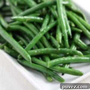 Sauteed garlicky green beans on a white rectangle shaped dish.