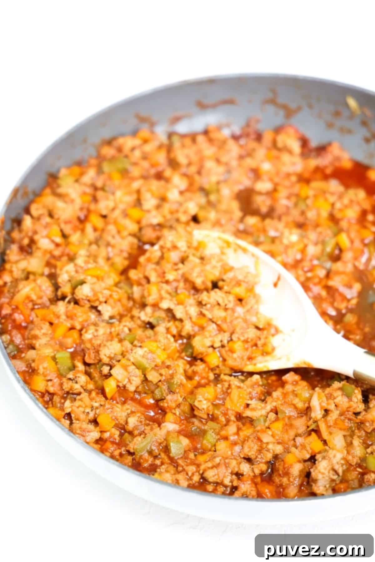 Ground turkey sloppy joe mixture in a skillet with a white serving spoon, ready to be served.