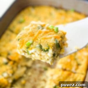 One piece of egg casserole held up by a white spatula over the rest of the casserole.