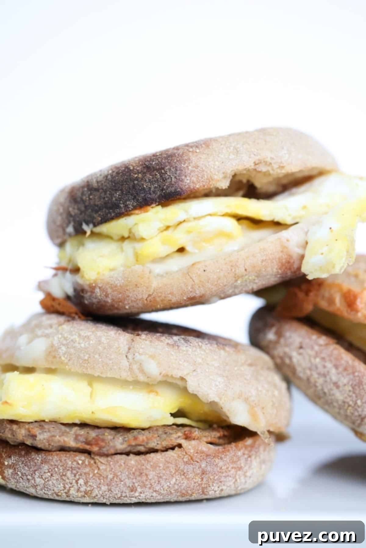 Three sausage, egg, and cheese sandwiches stacked.