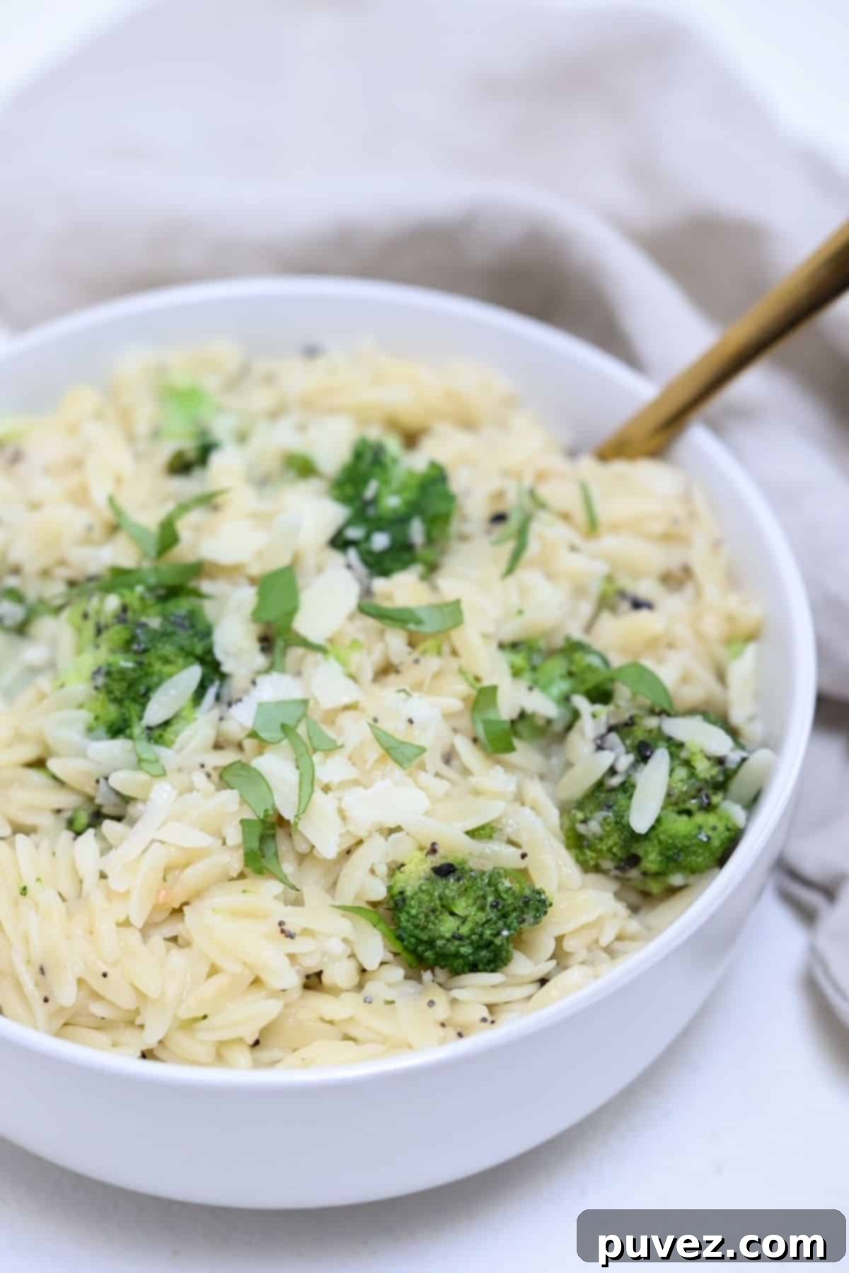 Quick and Creamy Broccoli Orzo 2 Orzo with broccoli in a white serving bowl with a gold serving spoon.