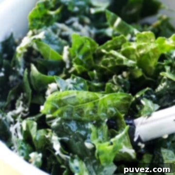 kale salad in a yellow bowl with tongs