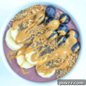 One acai protein bowl topped with fresh fruit, granola, and chia seeds, served in a white bowl.