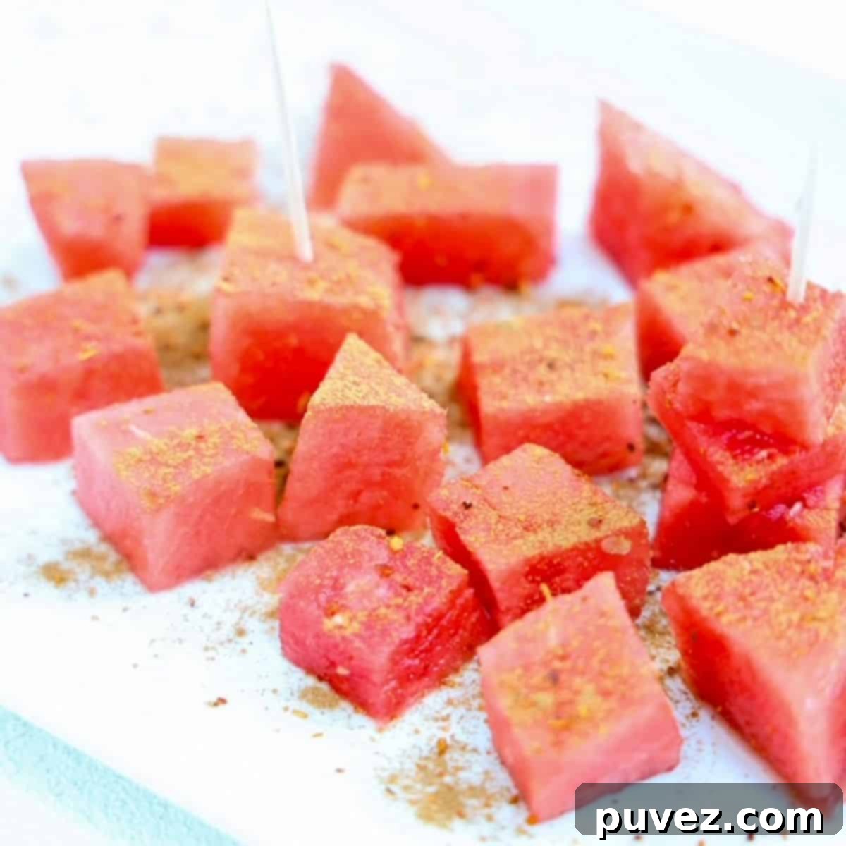 Chunks of fresh watermelon topped with Tajin and cinnamon, presented beautifully for a summer snack.