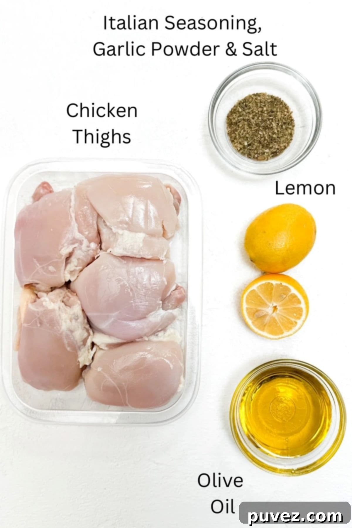Individual ingredients laid out for making baked Italian chicken, including chicken thighs, lemon, olive oil, and seasonings.