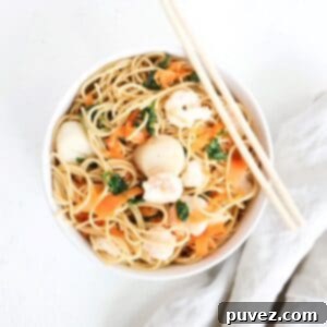 One Asian-inspired noodle bowl with a linen napkin on the side and chopsticks on top of the bowl.