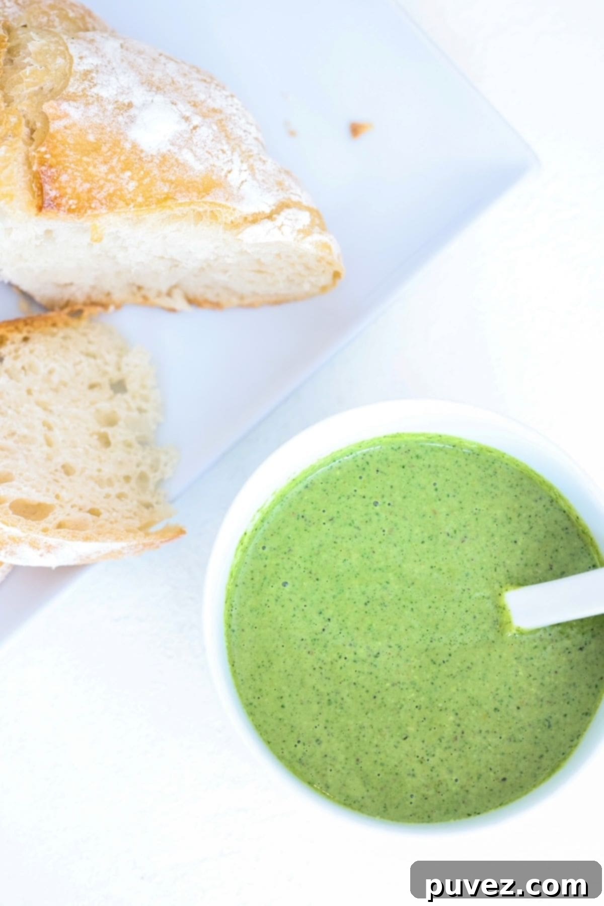 Pesto in a white bowl and two slices of sourdough bread on a white plate. A rustic, inviting image of fresh pistachio pesto, perfect for SEO.