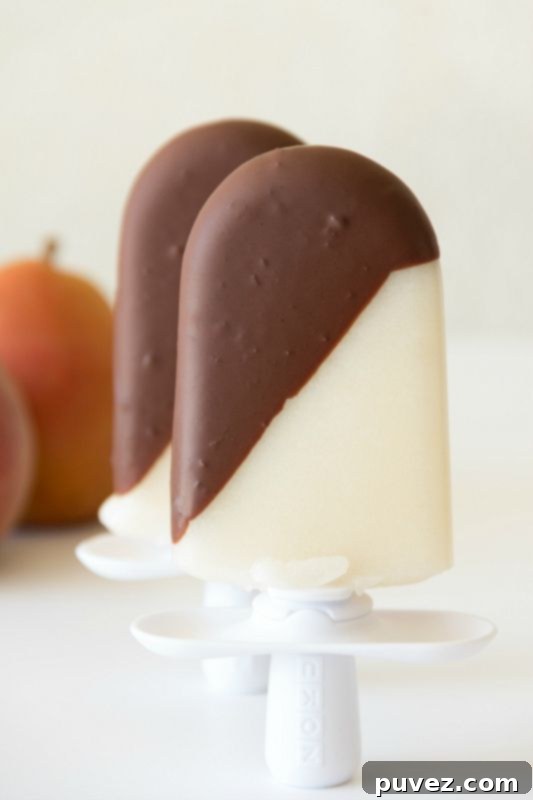 Elegant Chocolate Dipped Pear Popsicles, a sophisticated fruity and chocolatey frozen treat.