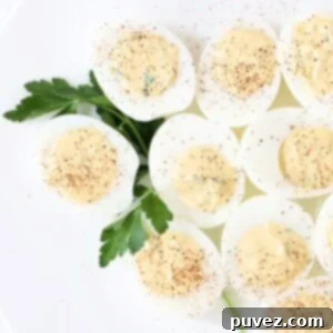 Effortless Mustard Free Deviled Eggs 5 Nine delicious deviled eggs, beautifully arranged on a white plate and garnished with a sprig of fresh parsley, showcasing their creamy filling and perfect presentation.