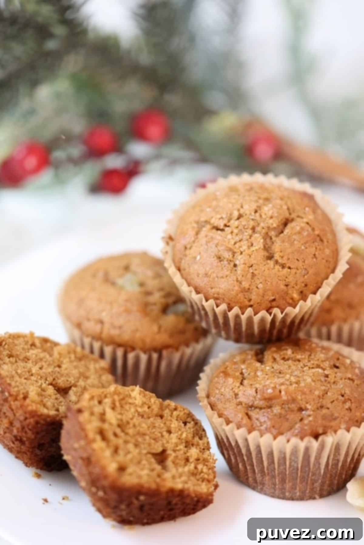 Gingerbread muffins on a white plate with a holly branch in the background.