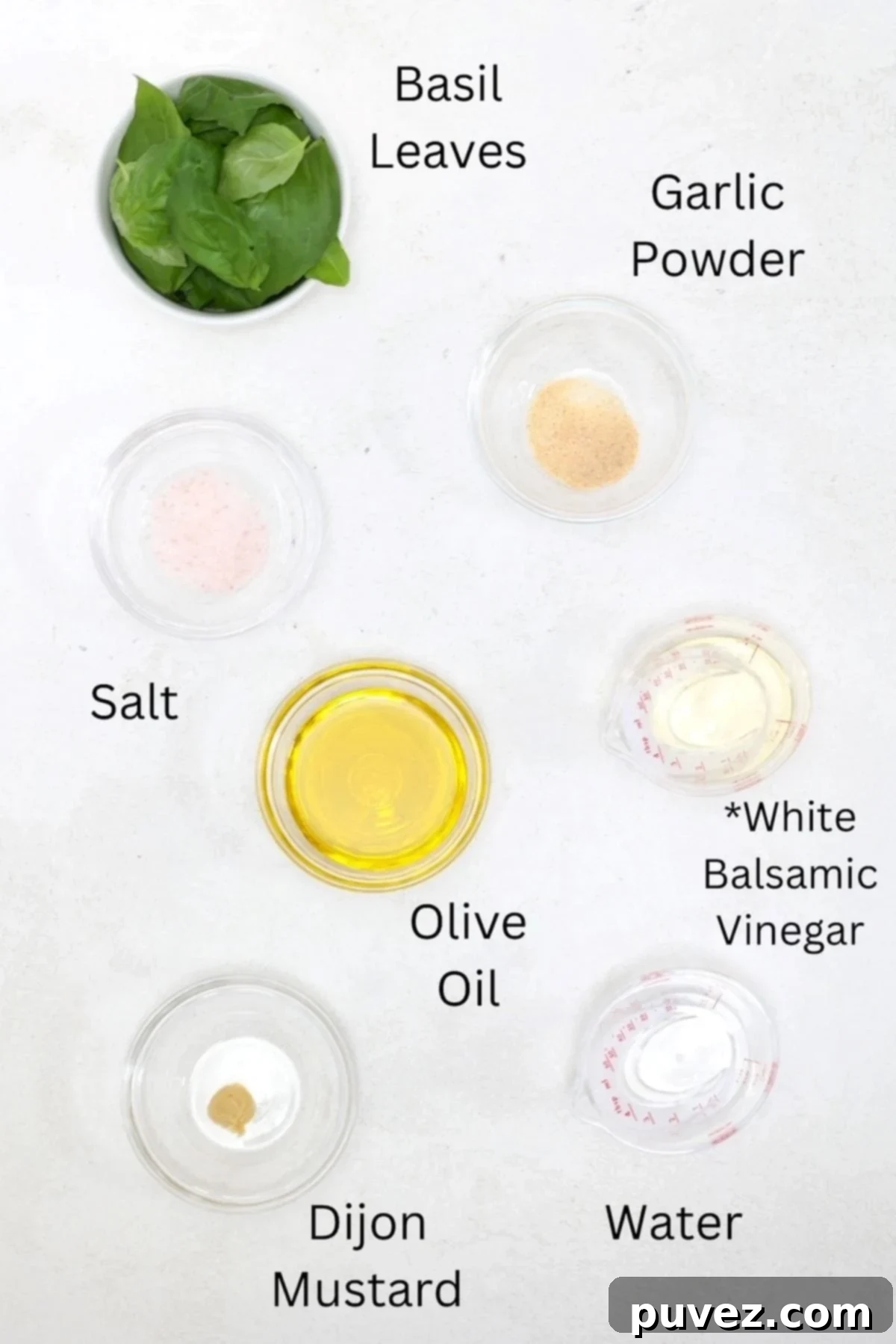Labeled ingredients for Basil Balsamic Vinaigrette, including fresh basil, white balsamic vinegar, olive oil, Dijon mustard, garlic, salt, and water.