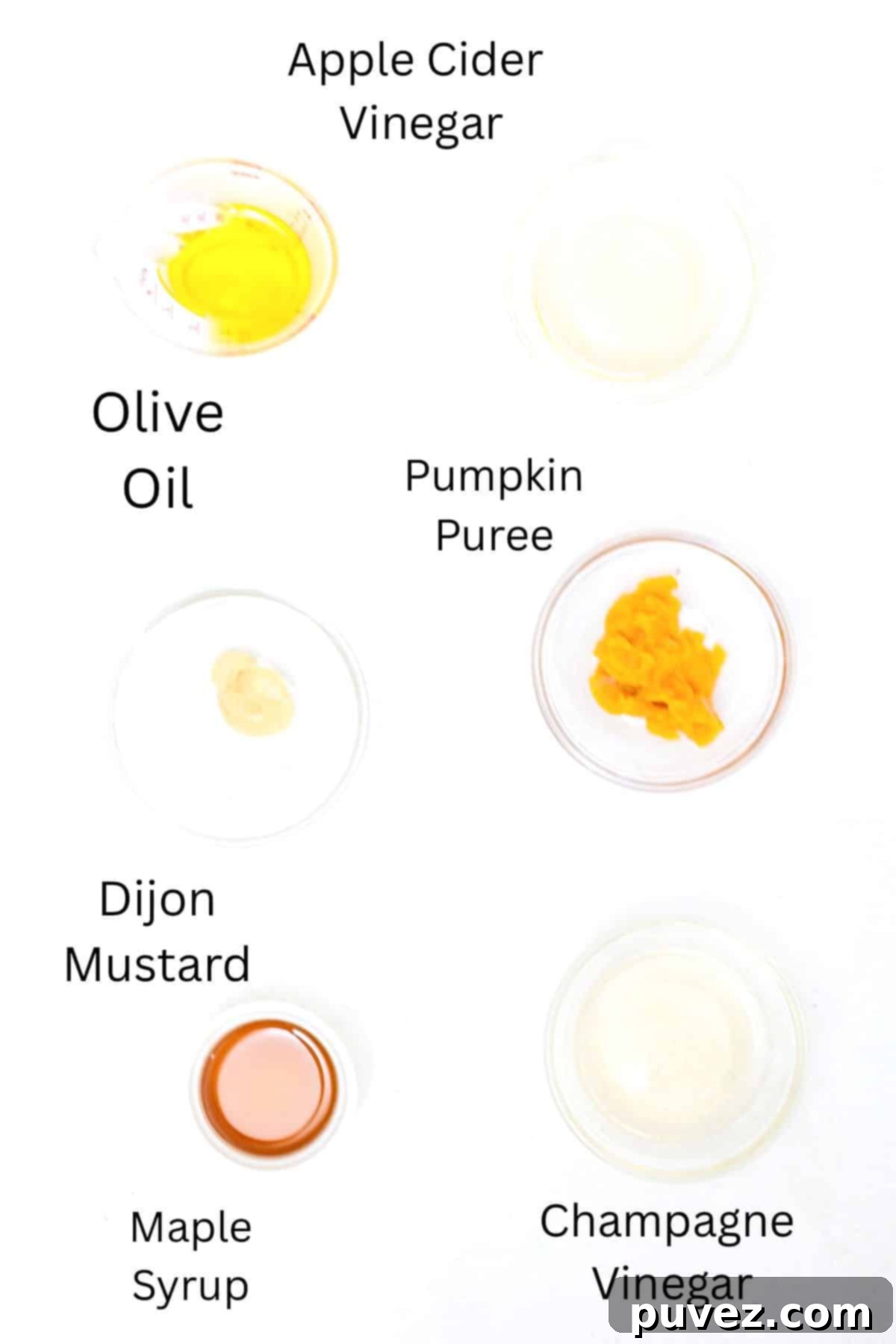 Bright Apple Vinaigrette 3 Individual ingredients for Apple Cider Vinaigrette Dressing, including vinegars, pumpkin puree, olive oil, maple syrup, and Dijon mustard, neatly arranged and labeled on a white surface.