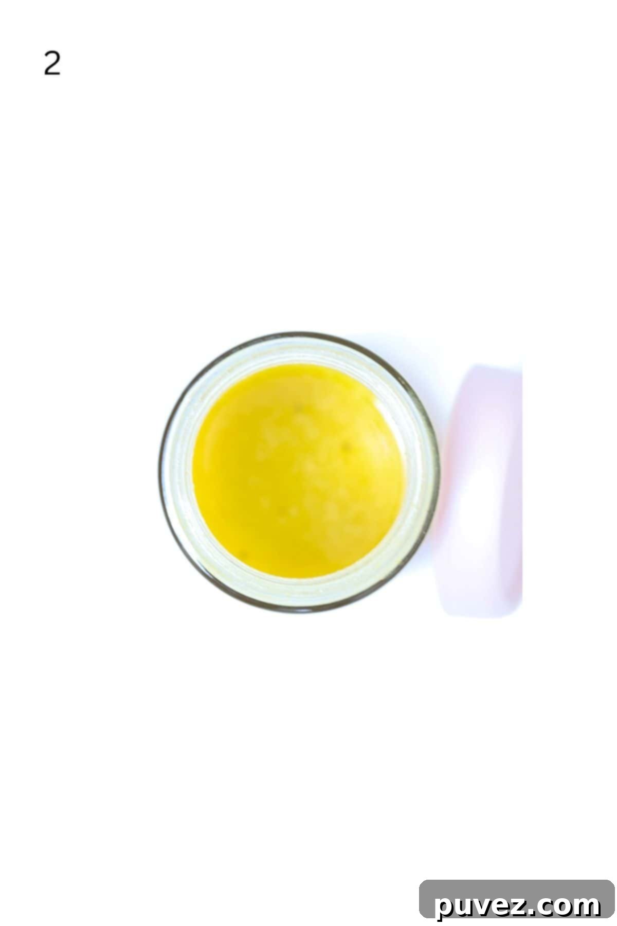 Bright Apple Vinaigrette 5 Top-down view of emulsified apple cider vinaigrette salad dressing in a glass jar, with the lid placed next to it, indicating it's ready for use or storage.
