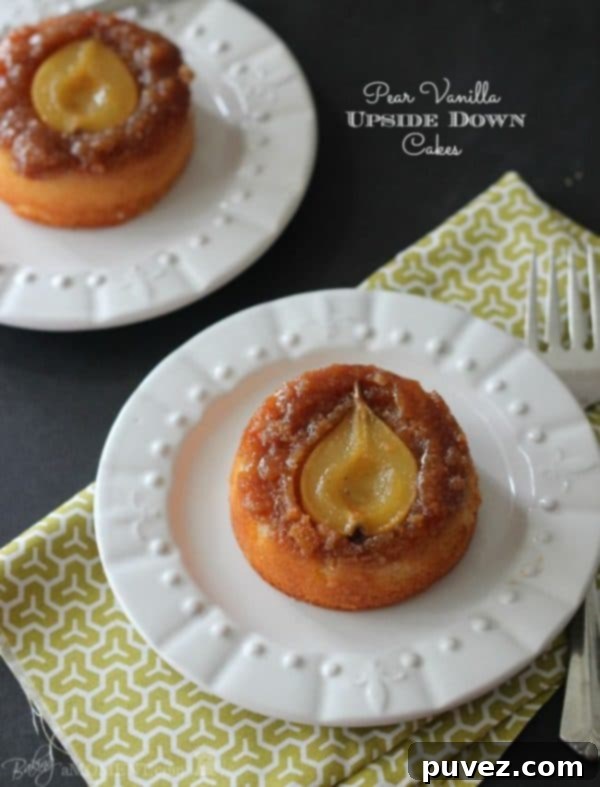 Individual Pear Vanilla Upside Down Cakes garnished with fresh herbs.
