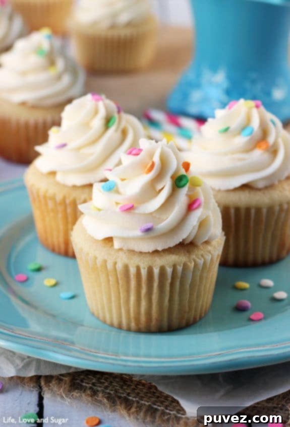 Perfectly frosted Moist and Fluffy Vanilla Cupcakes with decorative sprinkles.
