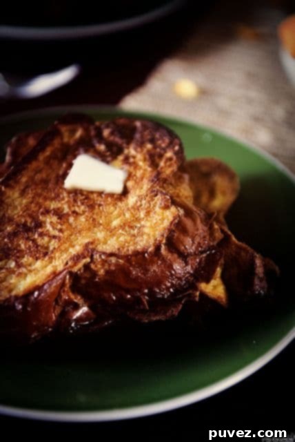 Plates of golden Vanilla French Toast drizzled with syrup and topped with berries.
