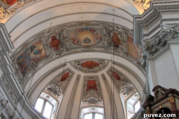 Intricate fresco and architectural details on the ceiling of Salzburg Cathedral's dome, a stunning baroque masterpiece.