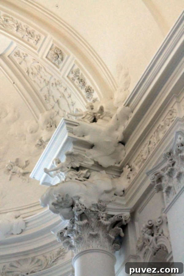 Close-up of intricate angelic sculpture and ceiling decor in Kollegienkirche Church, Salzburg.