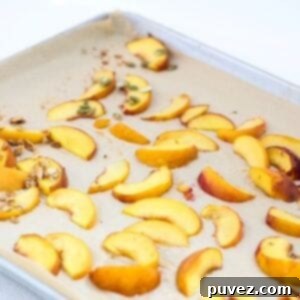 Roasted peach slices on a lined baking sheet, perfectly golden.